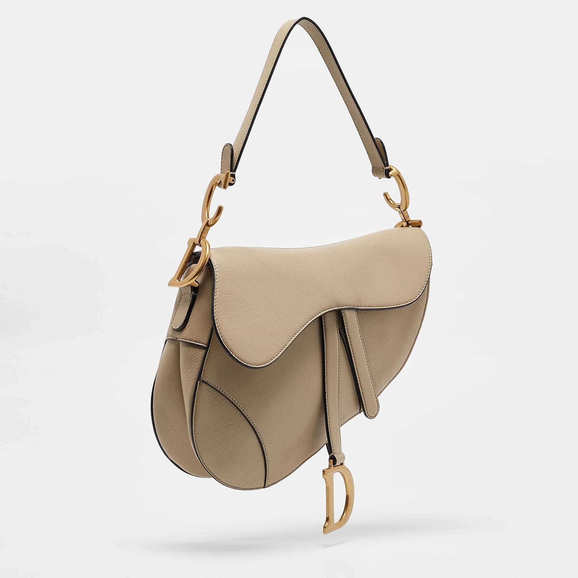 Side angle of Dior Saddle Bag with leather strap – luxury women’s handbag featuring sculptural shape and gold-tone hardware.