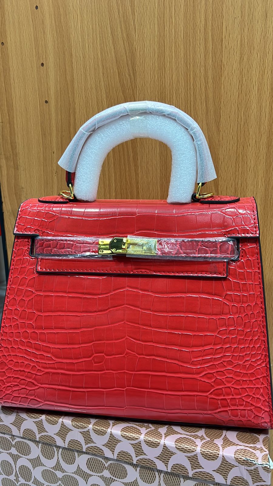  Side profile of Hermès Kelly 25 red crocodile bag displaying elegant stitching and compact silhouette.