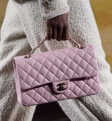 Side view of the Chanel Jumbo Classic Double Flap Bag in soft baby pink lambskin leather with gold hardware.