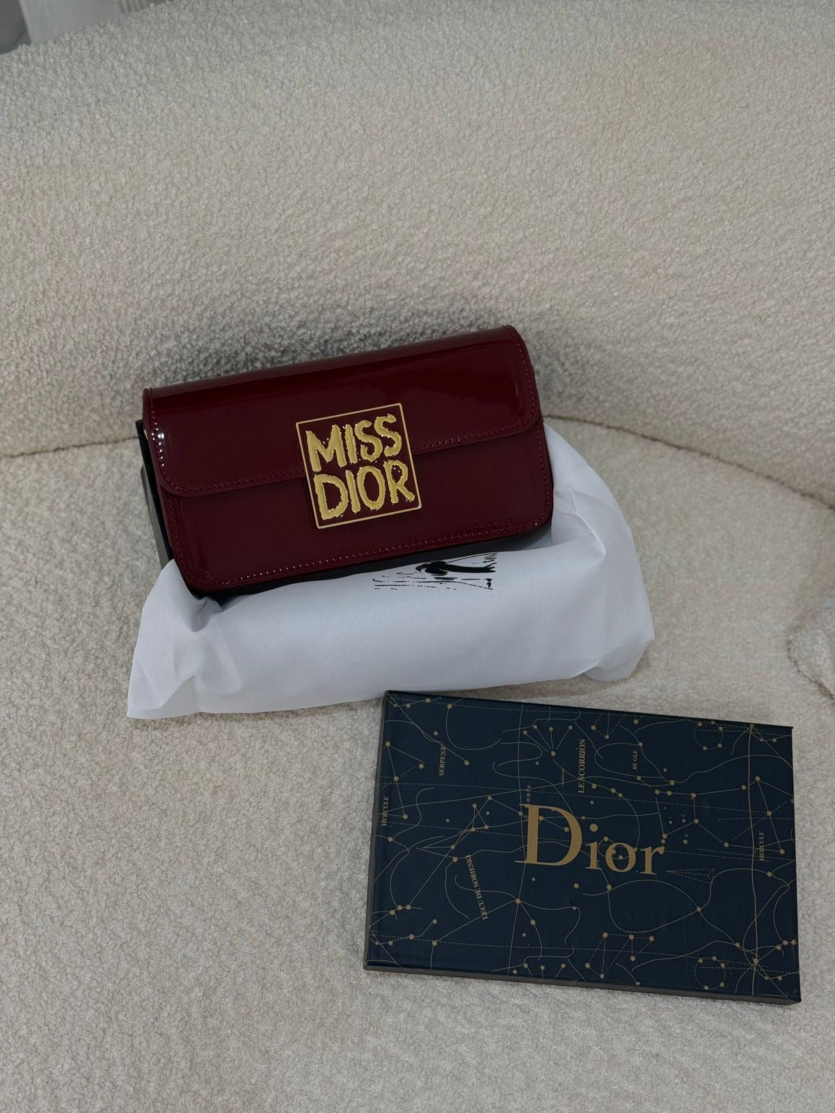Side profile of Dior calfskin shoulder bag – luxurious patent leather with sleek shape and Dior charm accent.