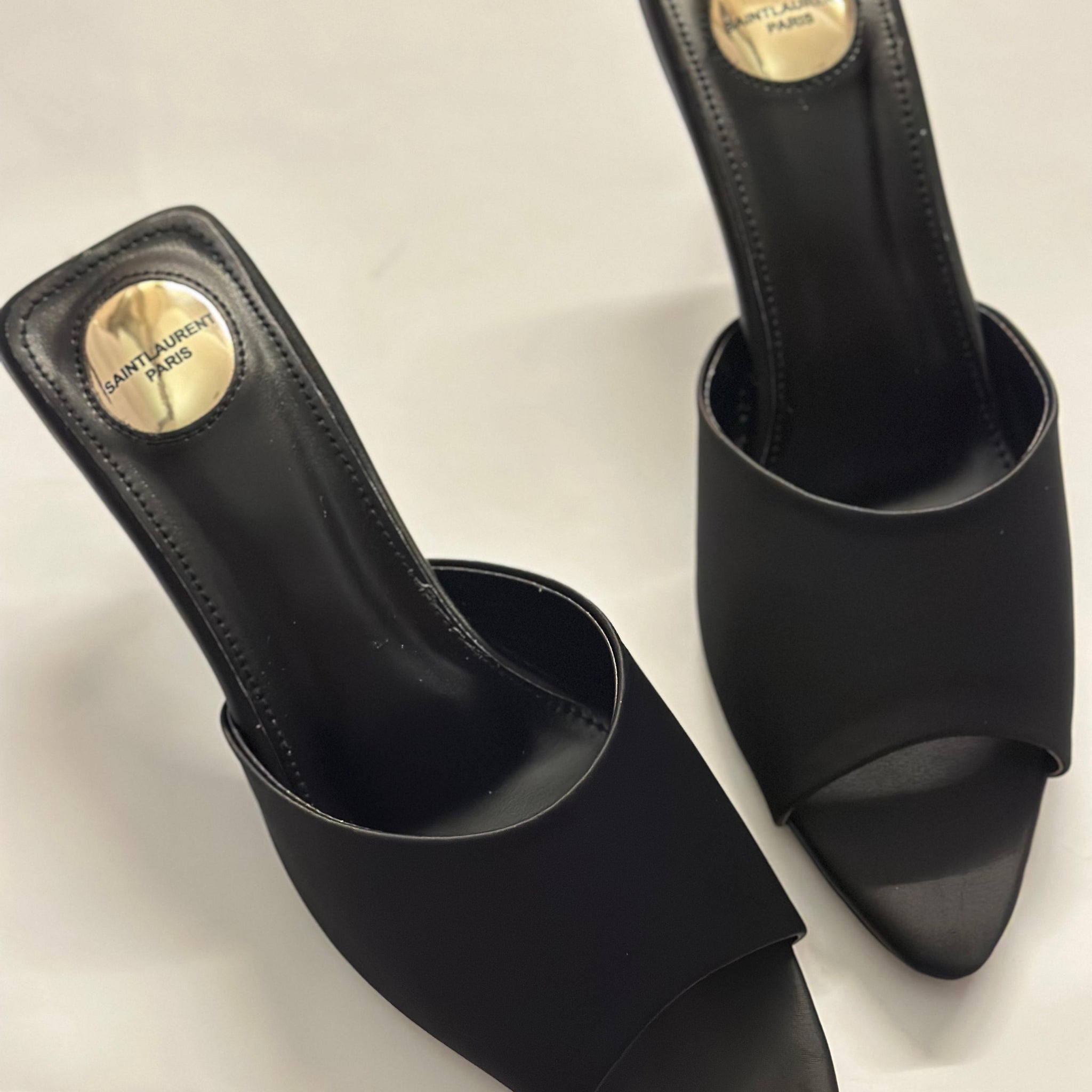 Front view of YSL black slide heels – elegant women’s designer shoes featuring sleek leather straps and open-toe design.