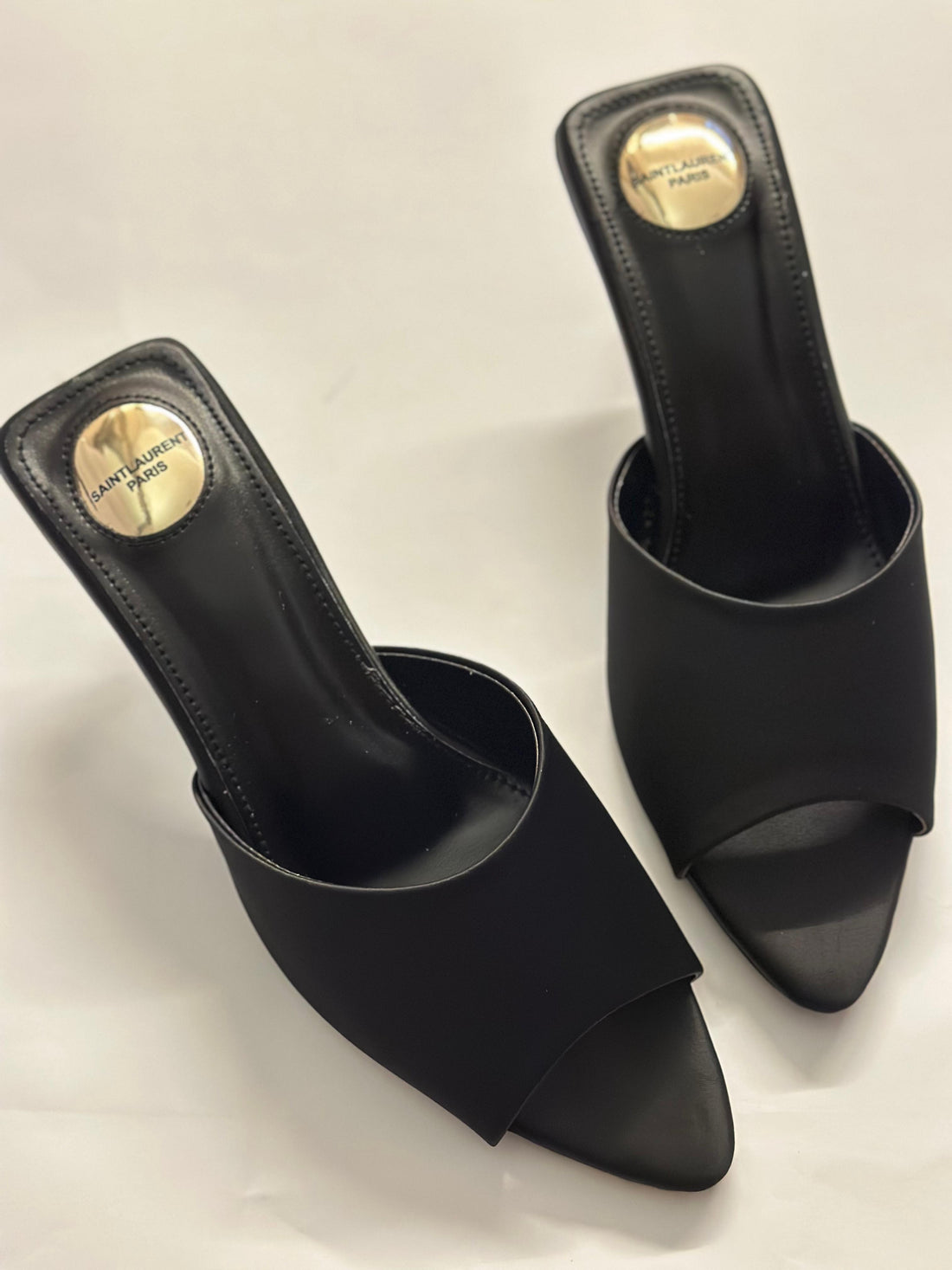 Front view of YSL black slide heels – elegant women’s designer shoes featuring sleek leather straps and open-toe design.