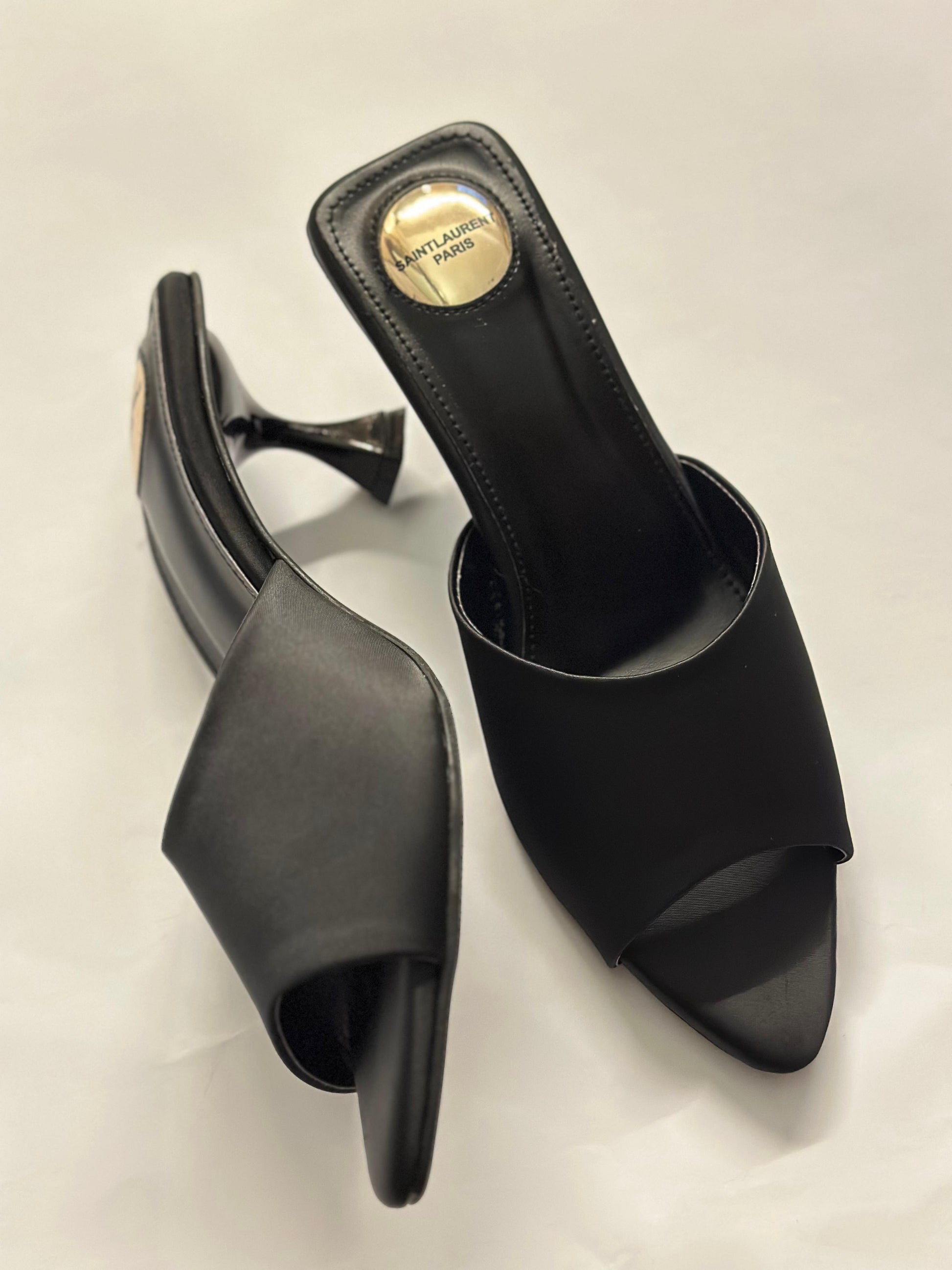 Side profile of YSL black slide heels – showcasing minimalist silhouette with signature YSL block heel and glossy black finish.