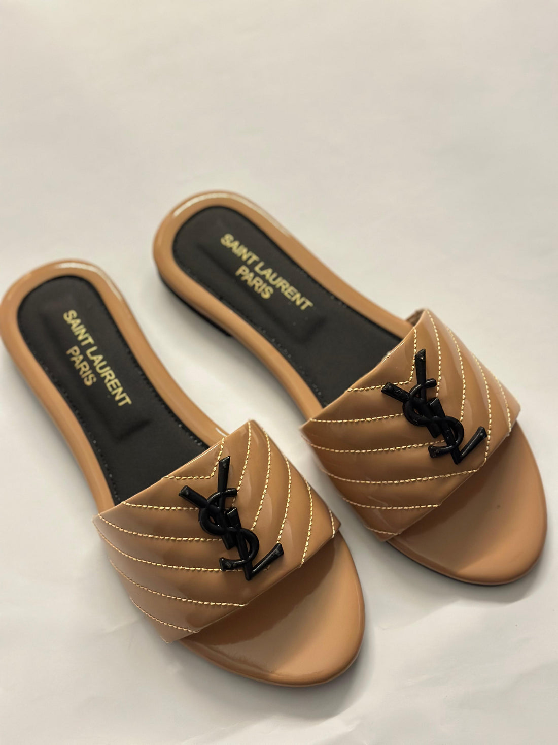 Front view of YSL flat slides – luxury women’s sandals with signature YSL logo and minimalist leather design.